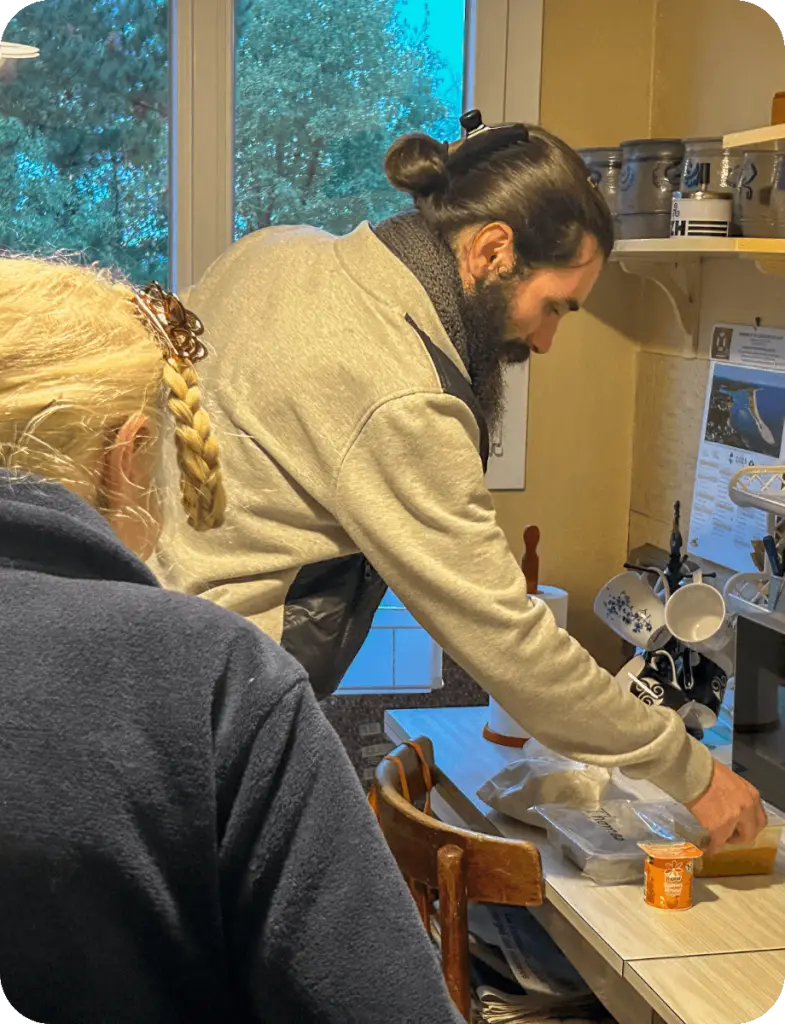 Un intervenant de l'association Le Connétable livre un repas à domicile à Dinan. Il dispose les plats sur la table de la cuisine devant la bénéficiaire.