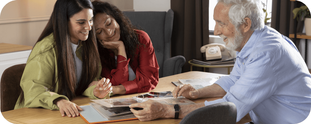 Moment de complicité et de partage de souvenirs entre un bénéficiaire et deux intervenantes – Association Le Connetable à Dinan, illustrant la lutte contre l’isolement à domicile