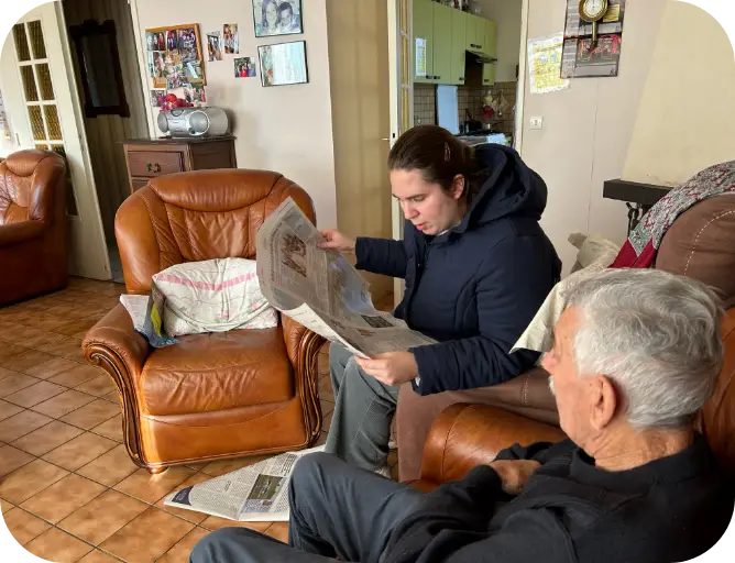 Un animateur à domicile chez une personne en train de lire le journal. Service proposé par l'Association Le Connétable